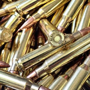 Close-up of brass rifle cartridges with copper tips piled together, in a cluttered heap.