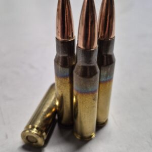 Three copper-jacketed rifle bullets standing upright in brass casings on a light background, close-up shot